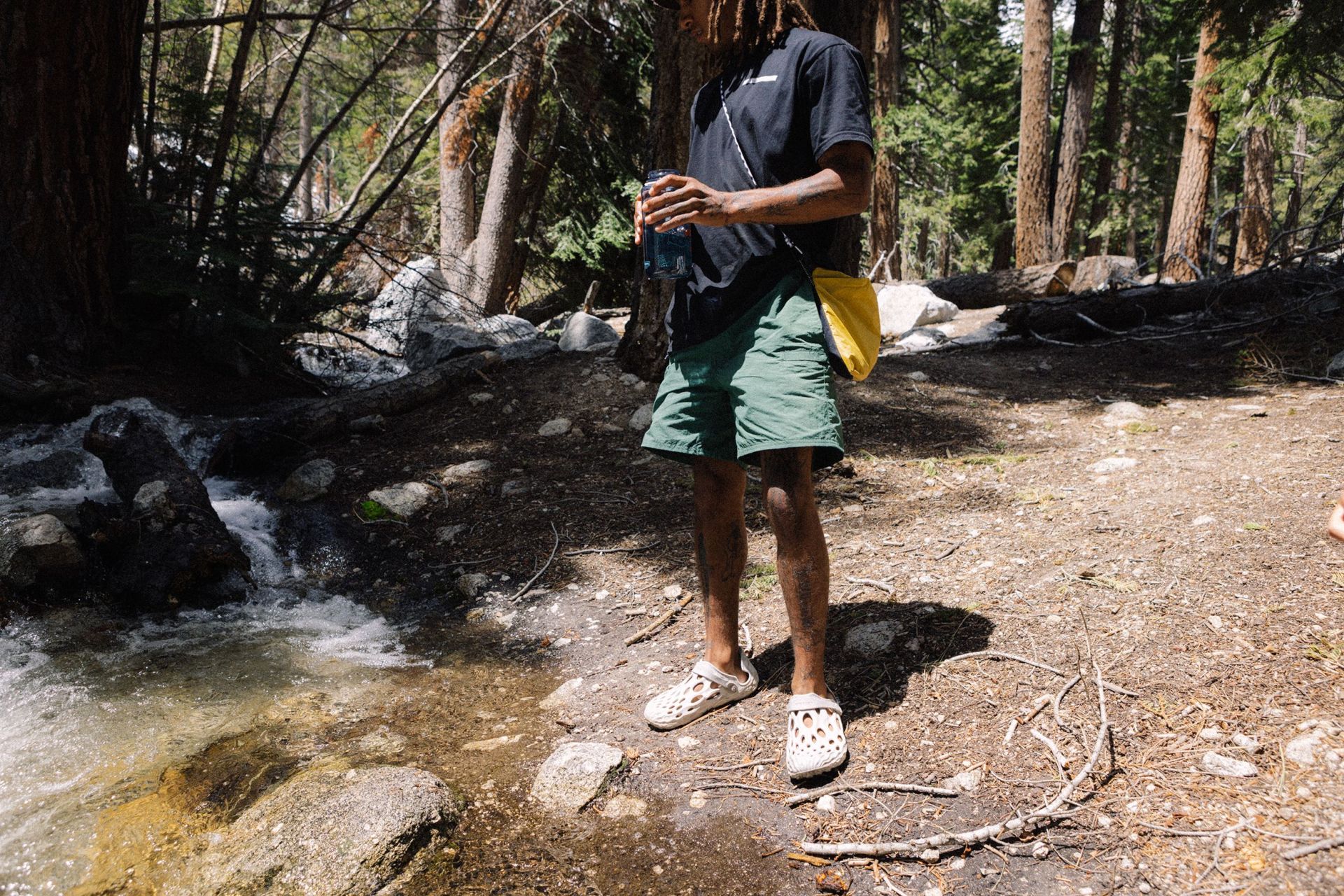 a person standing in the woods next to water