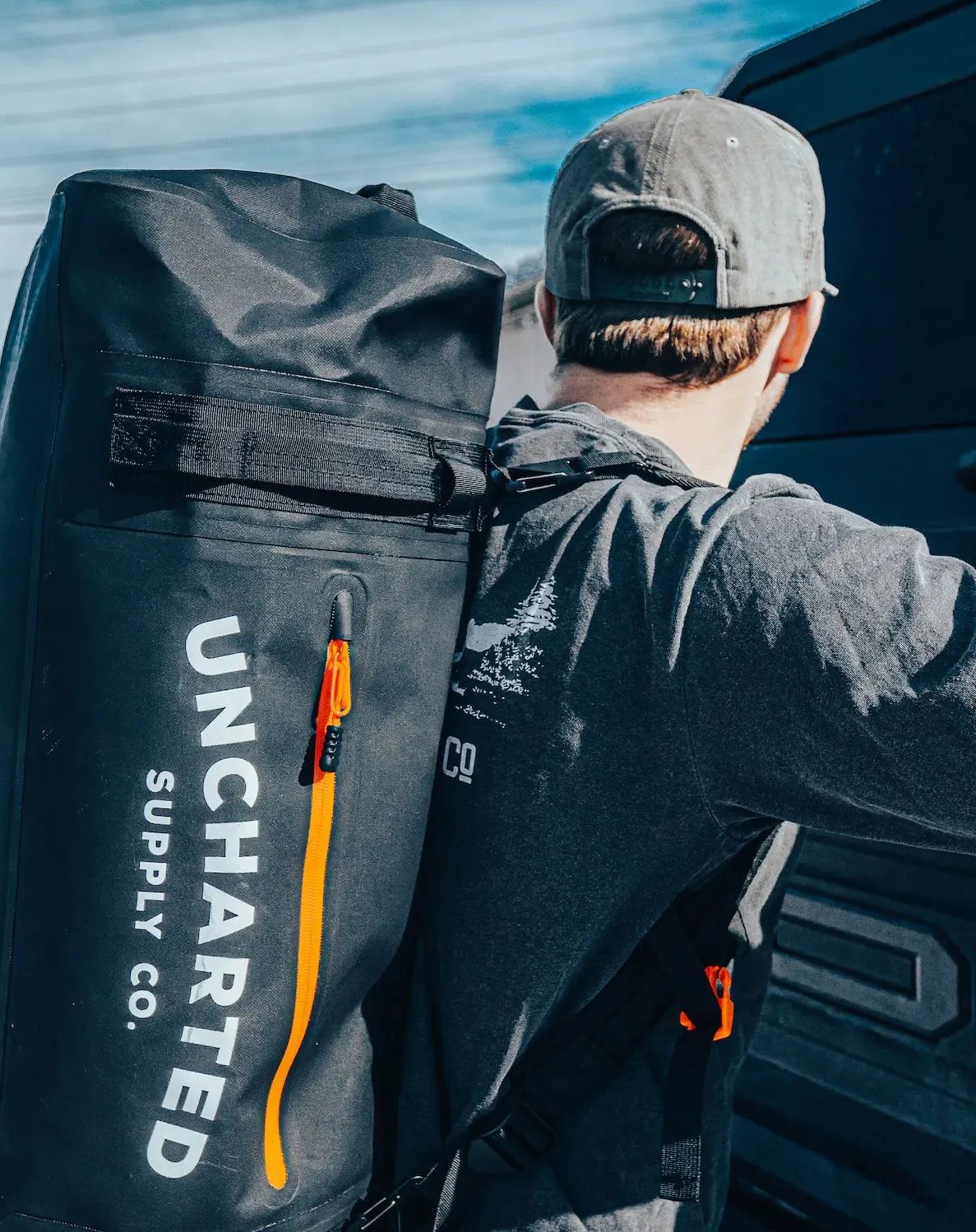 man carrying uncharted supply co the vault waterproof adventure duffel bag in black