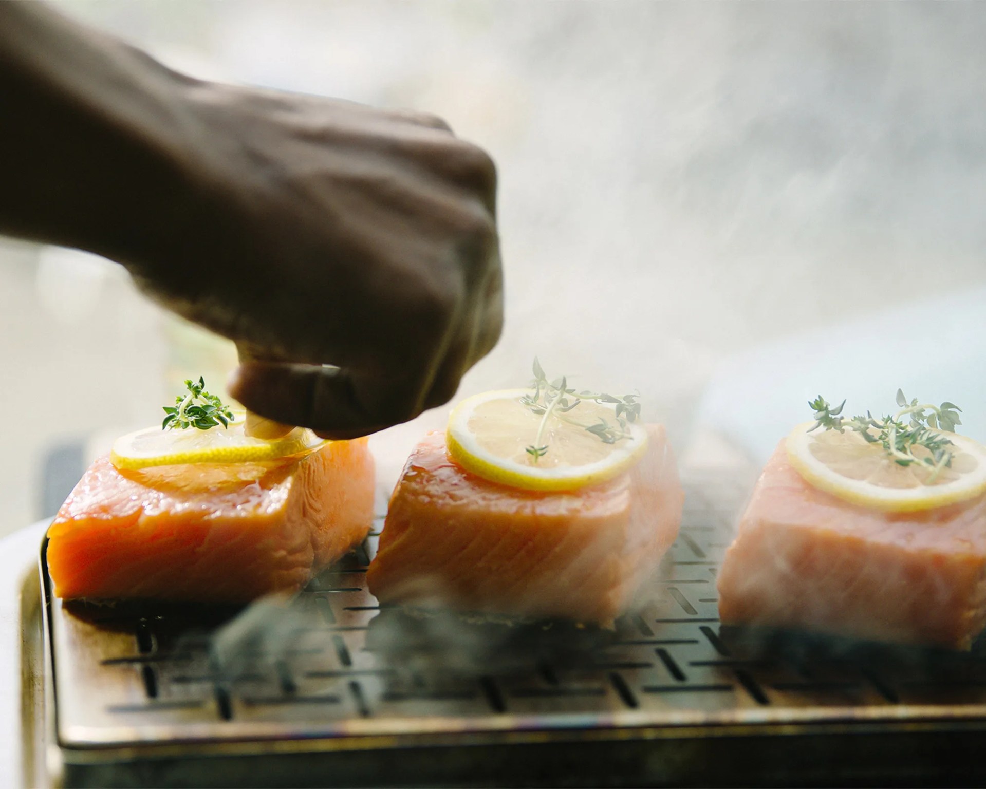 man seasoning salmon being grilled on weber grill