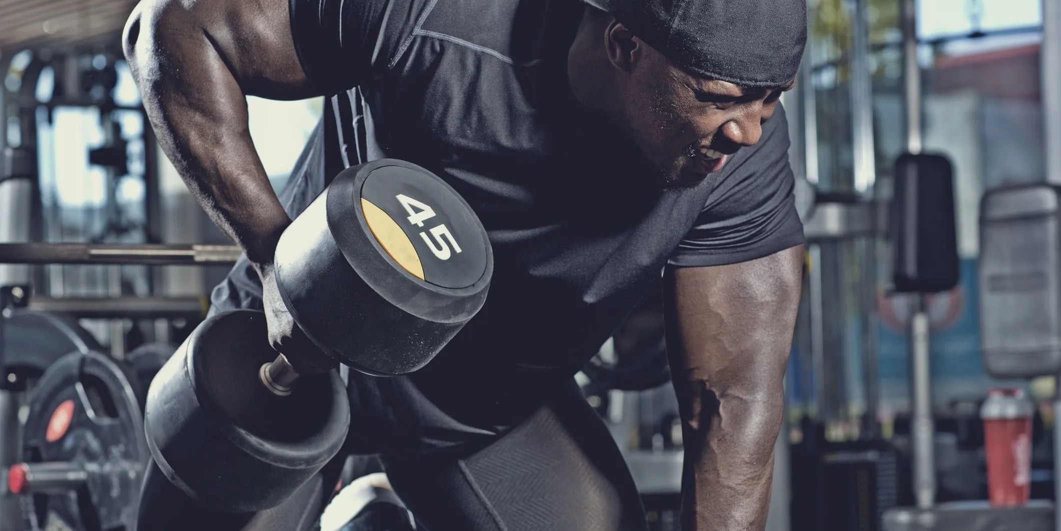 black male lifting dumbbells at a gym