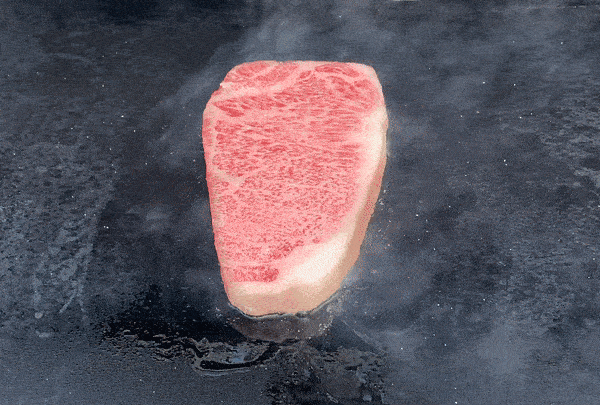 a steak cooking on a gas grill griddle