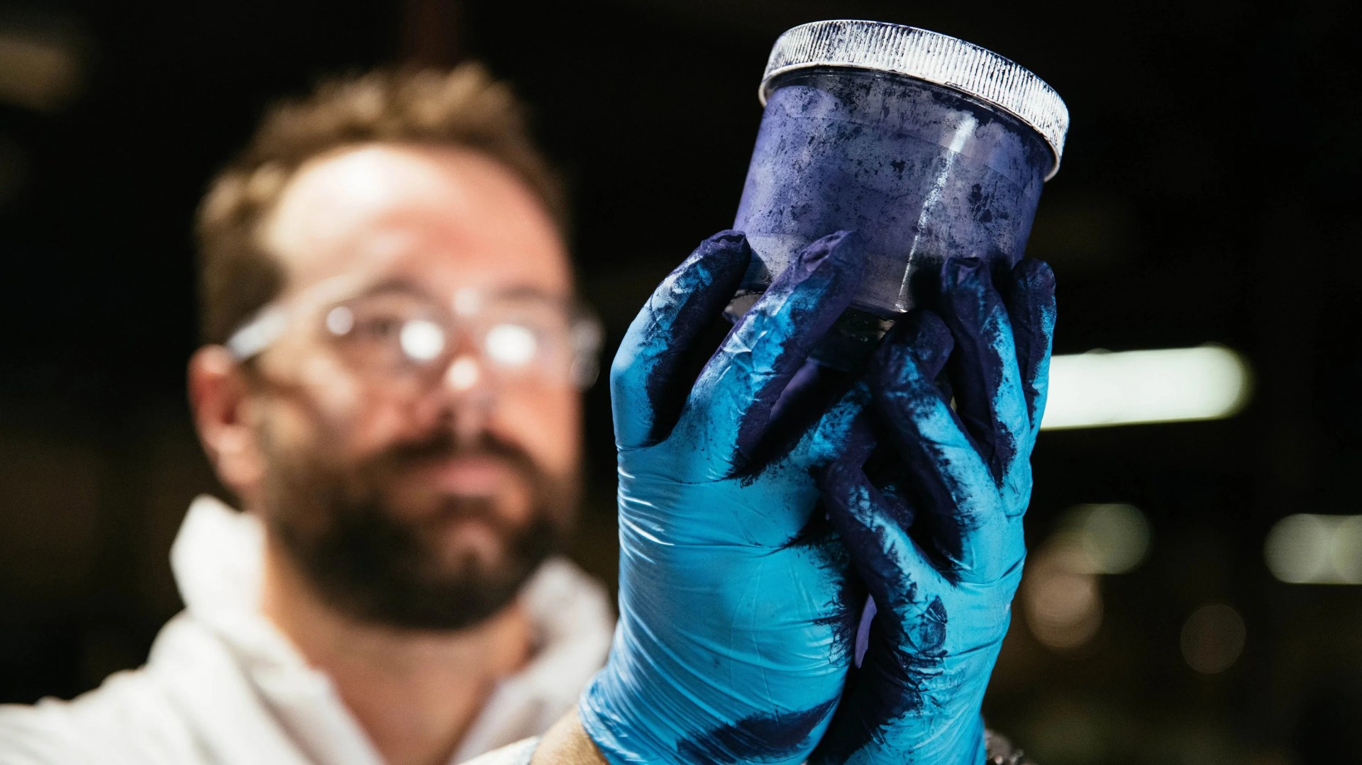 worker looking at indigo dye with blue gloves