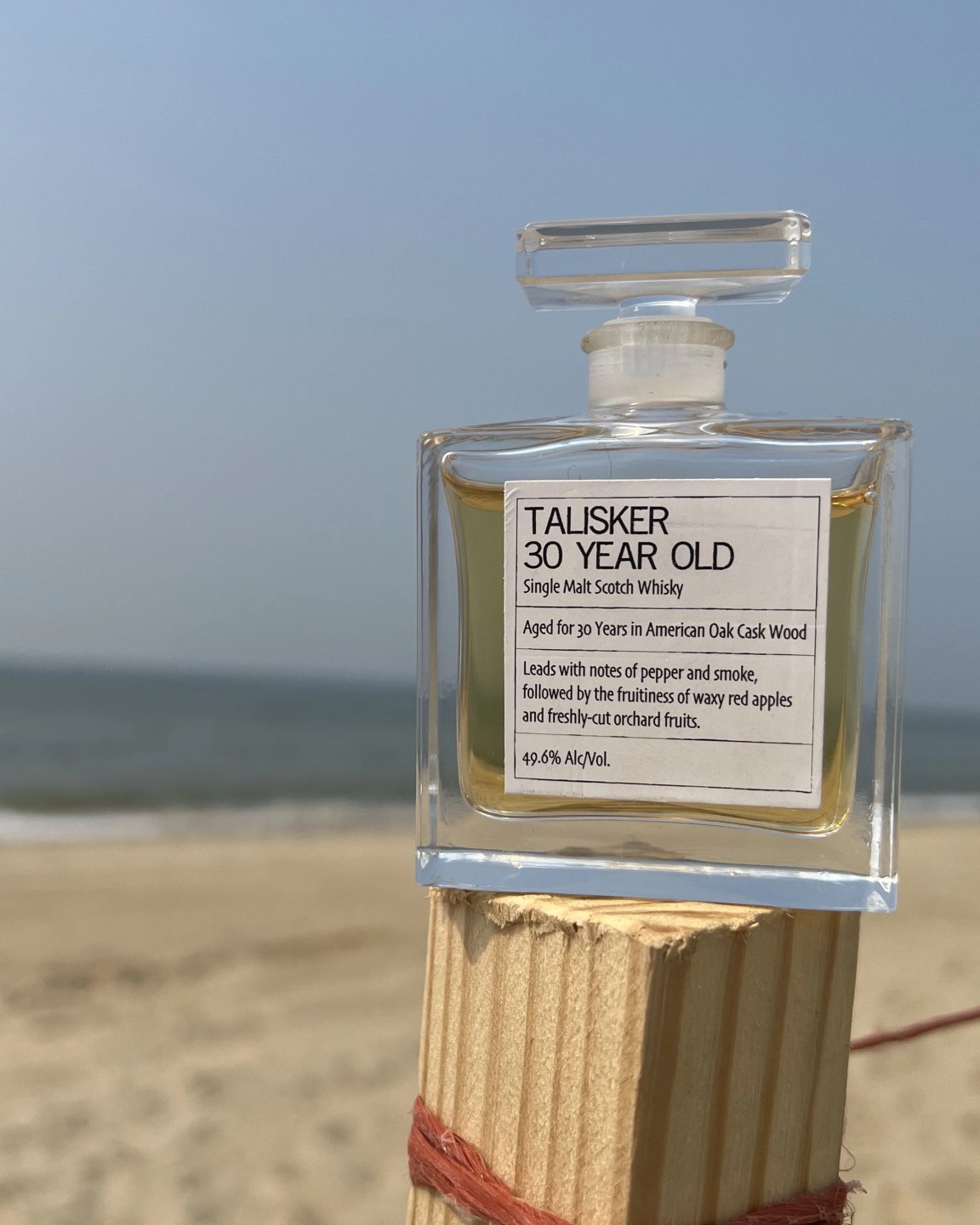 a sample bottle of talisker 30 year old scotch on a beach