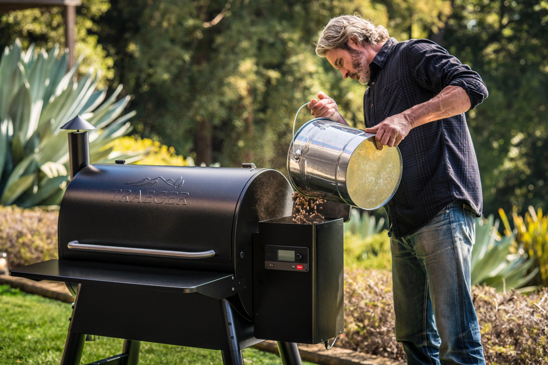 man adding wood pellets to a traeger grill