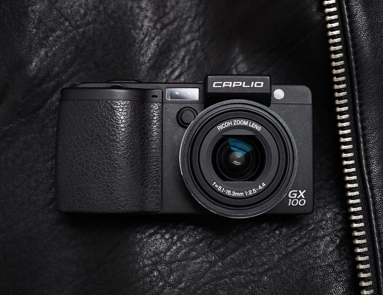 old school camera laying on a black leather jacket