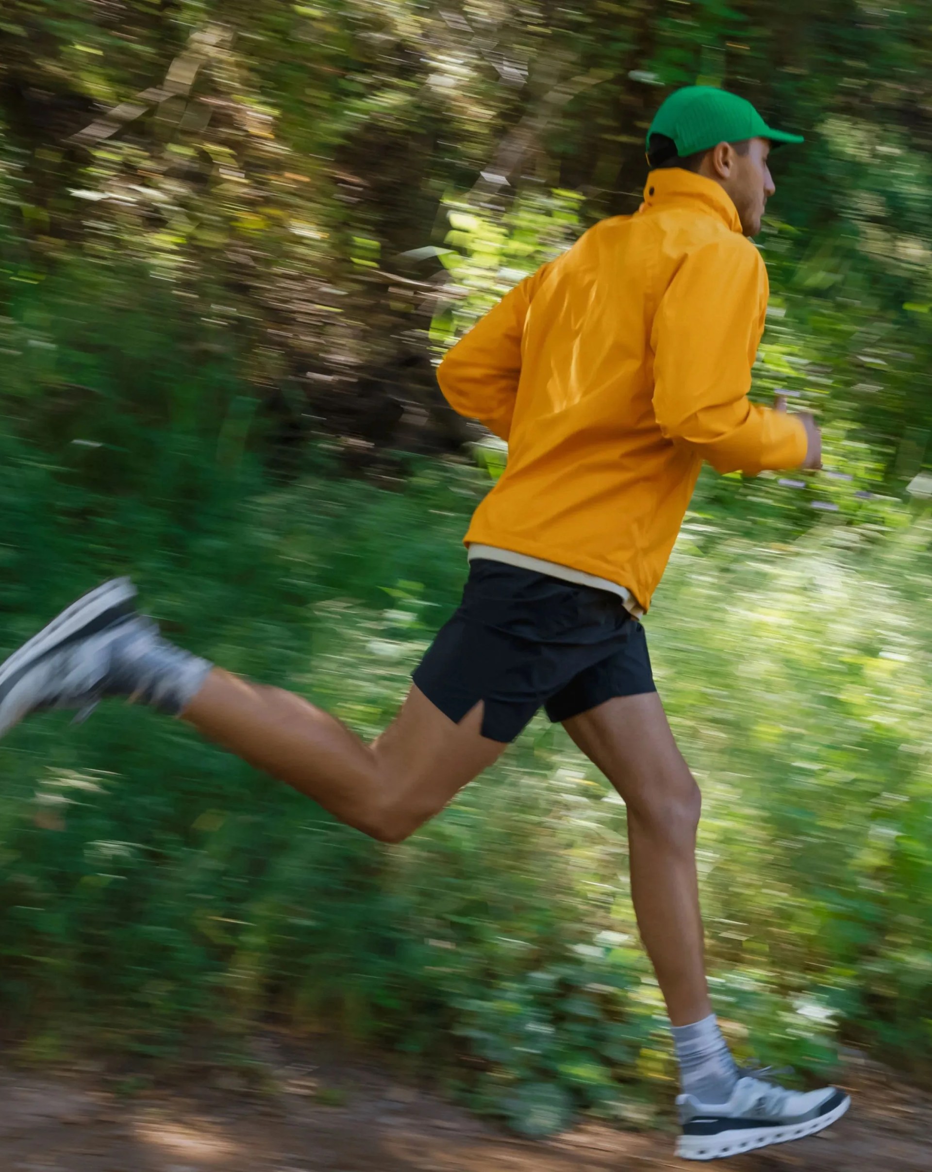 man running on trail wearing rivian adventure jacket