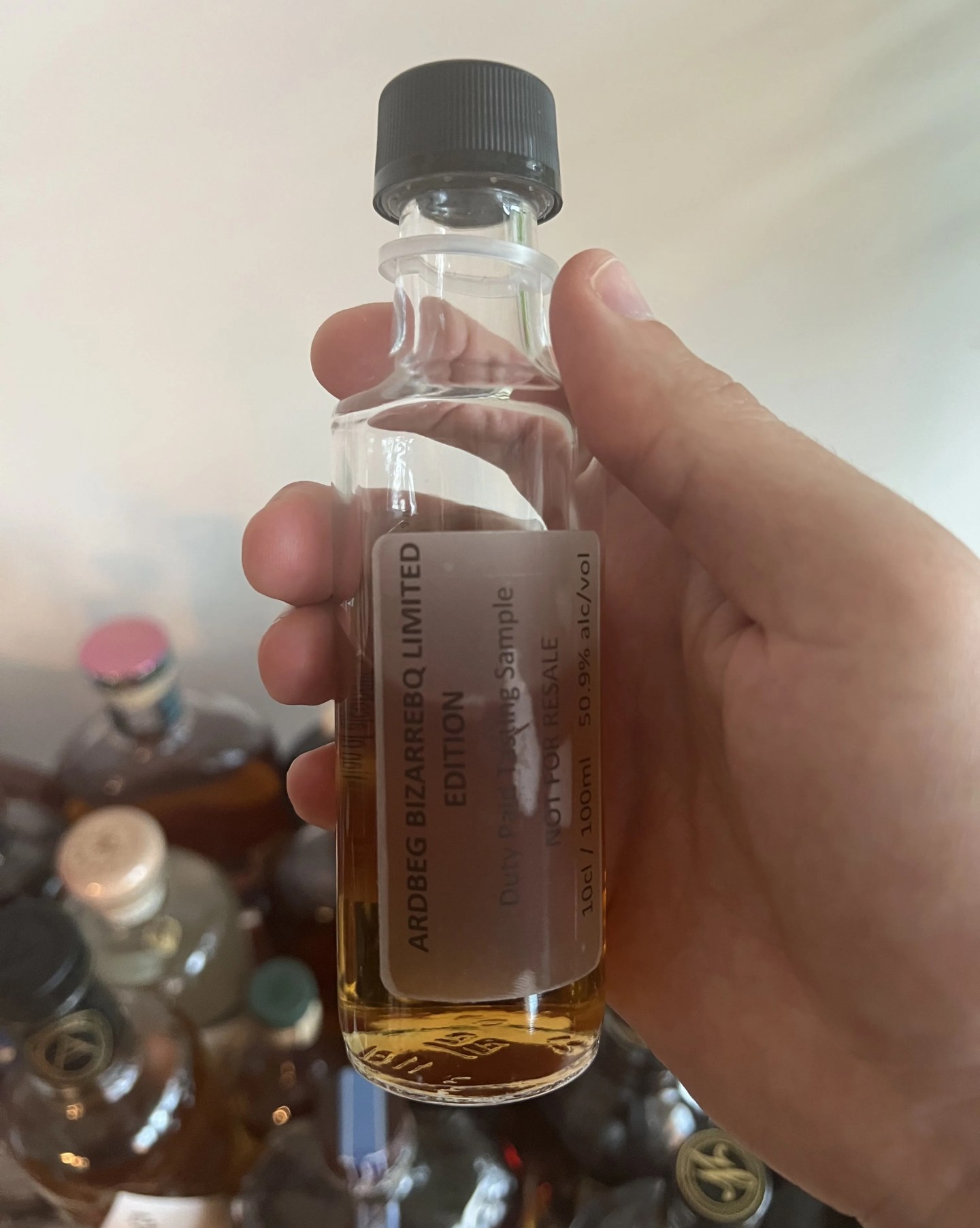 a hand holds a sample of ardbeg bizarrebq scotch whisky