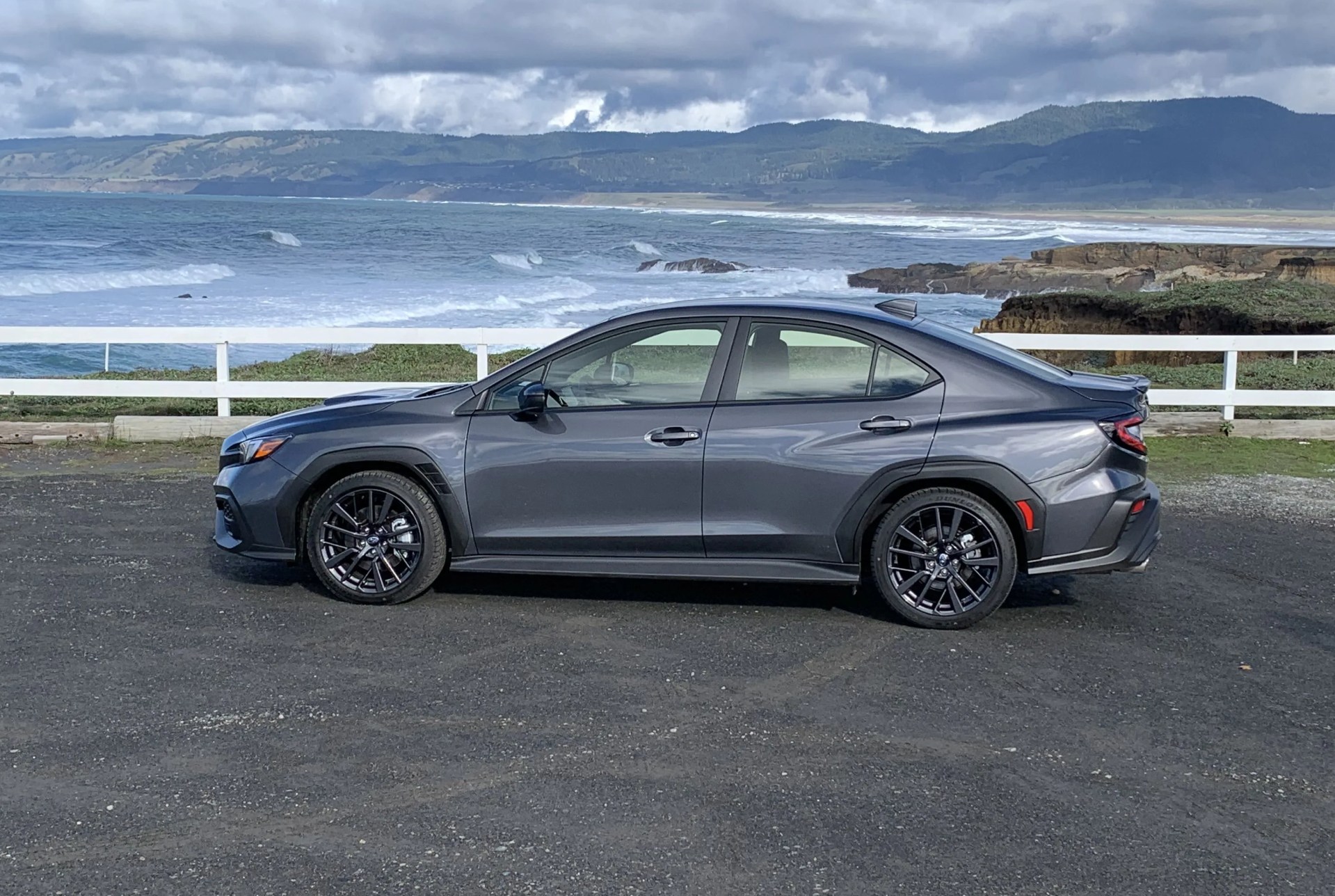 subaru wrx parked by a fence with northern california coastline in the background