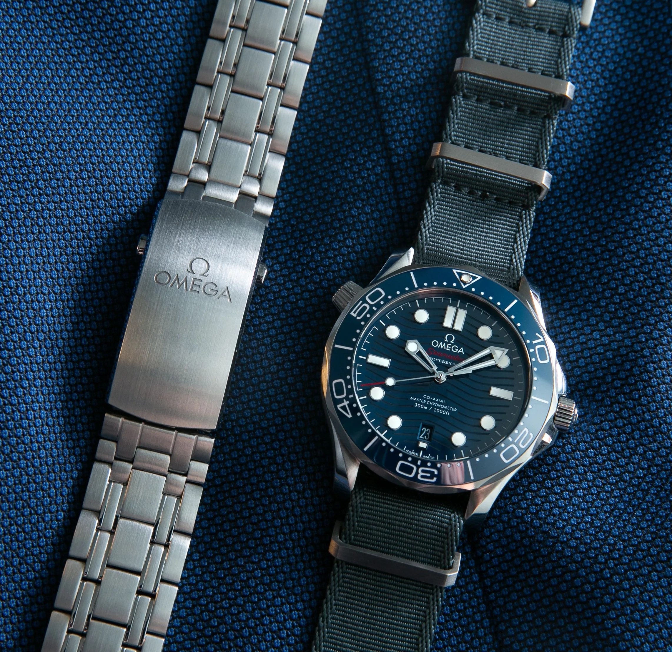 omega watch on a nato strap next to its steel bracelet