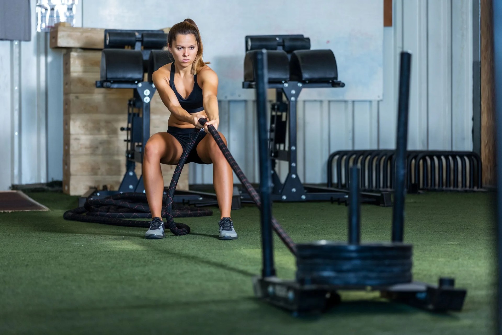 young sportswoman pulling rope with weight