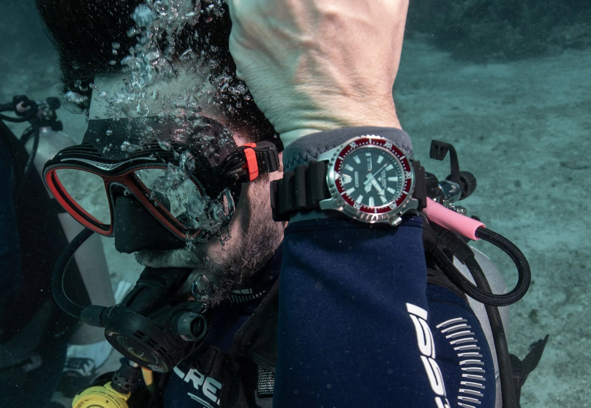 diver under water with red bezel dive watch