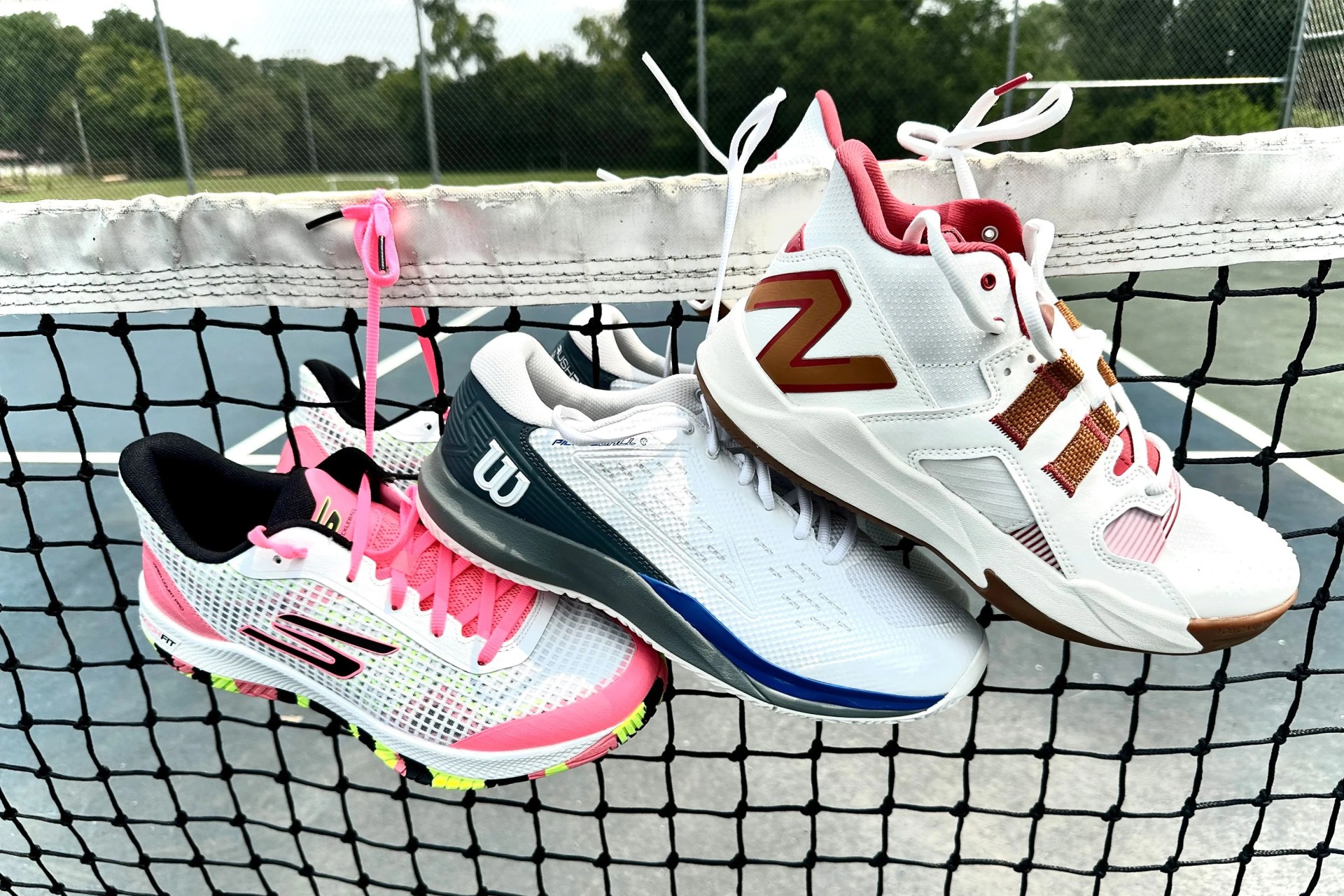 three pairs of pickleball shoes on a net