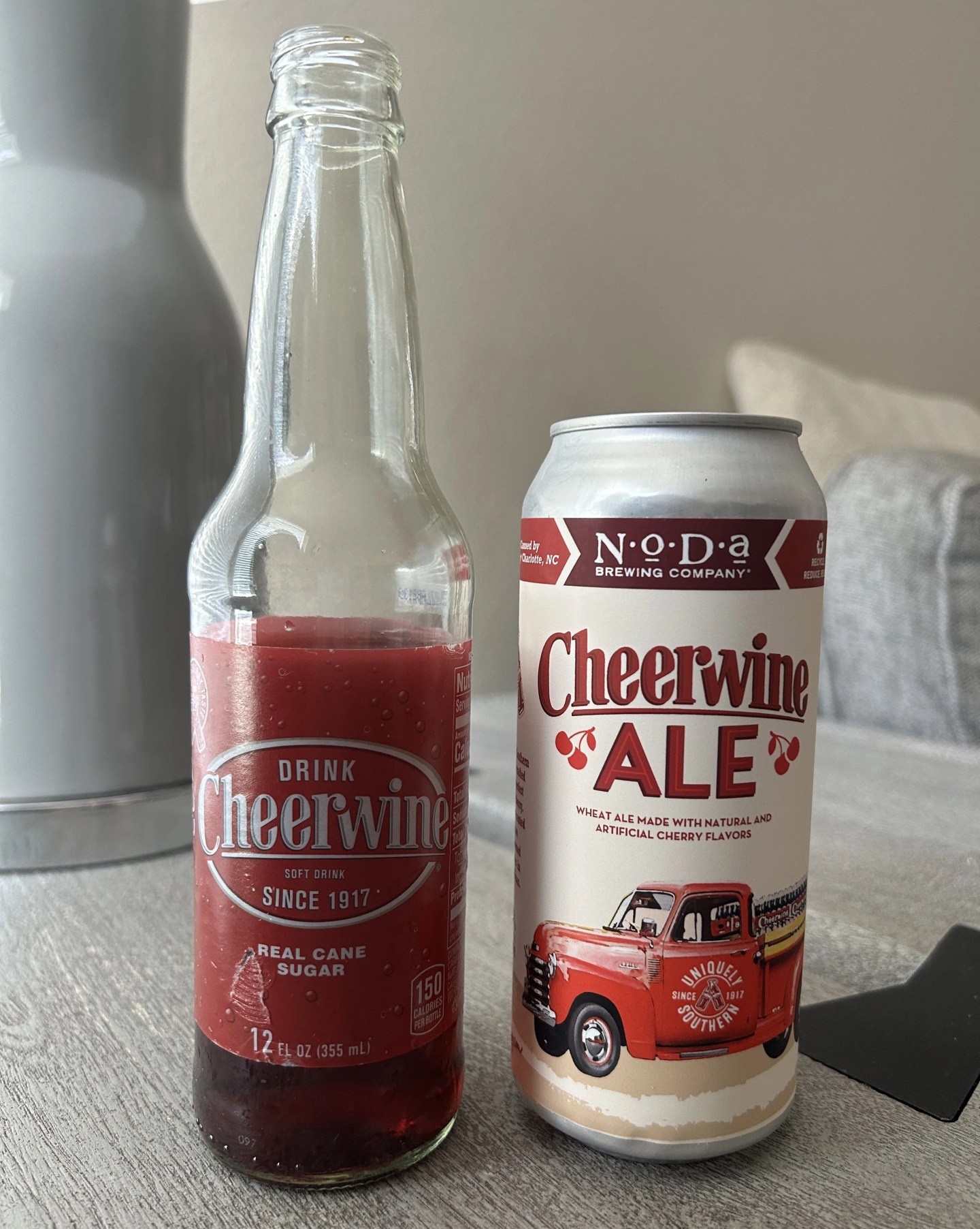 a bottle of cheerwine soda next to a can of cheerwine ale