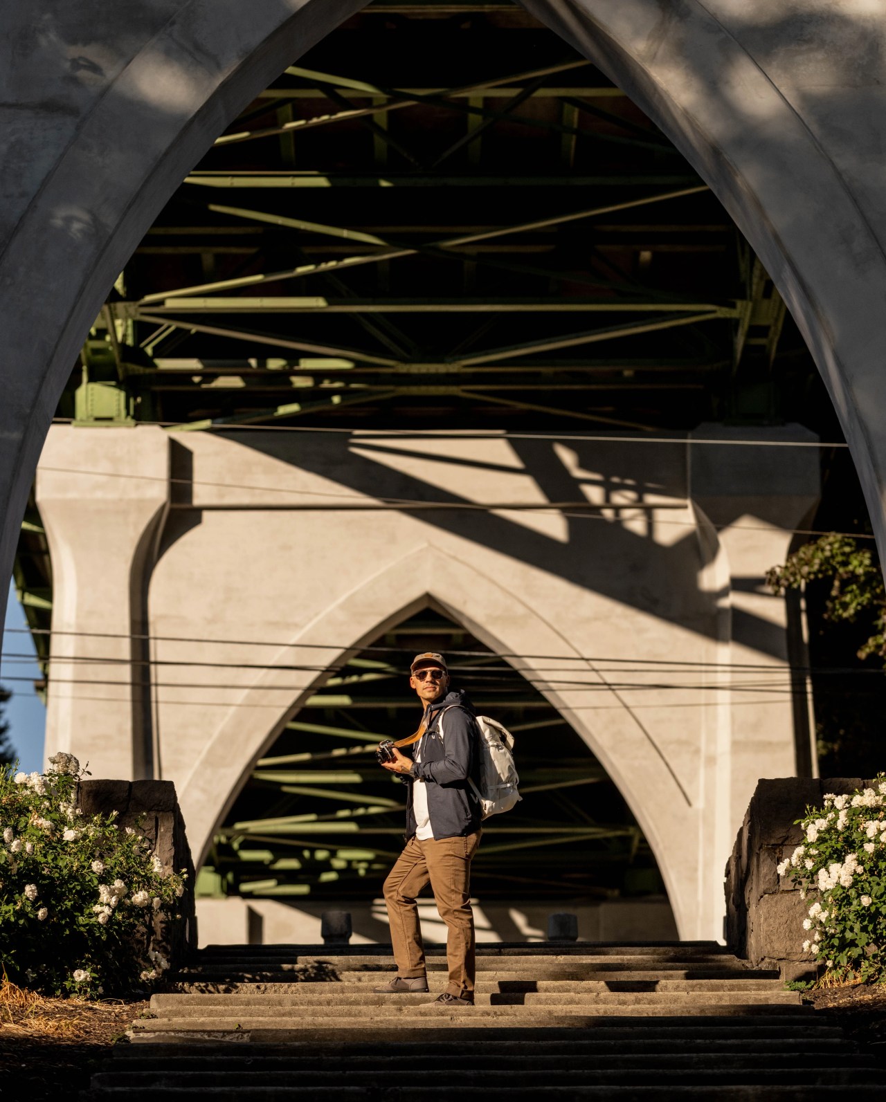 man standing with camera carrying white camelbak backpack