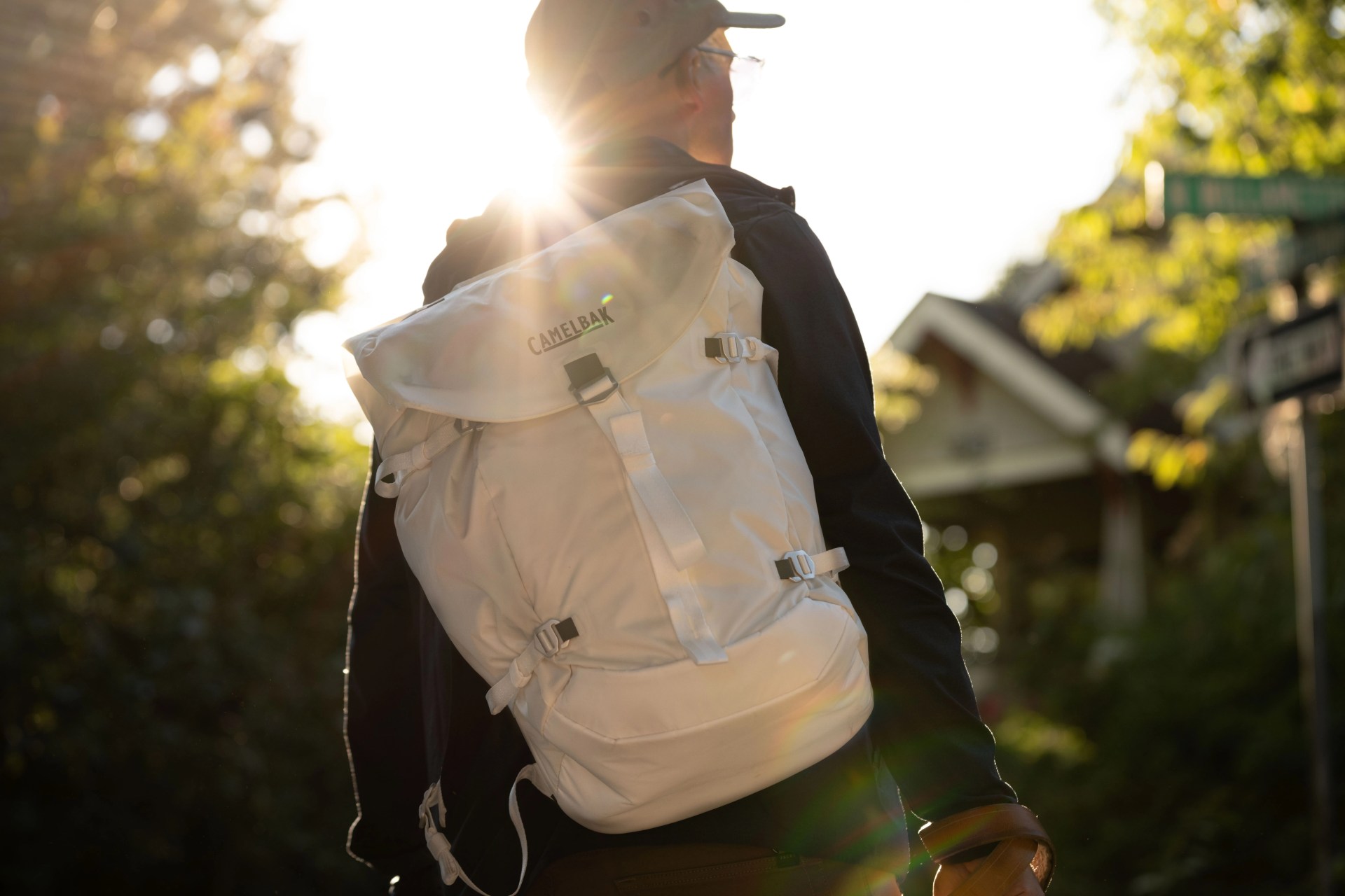 man walking carrying white camelbak backpack