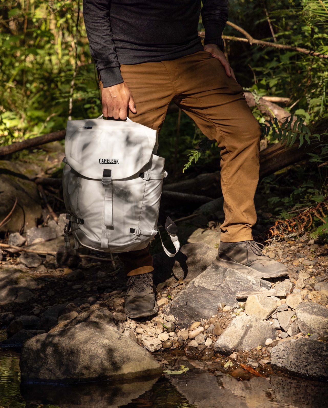 man standing holding white camelbak backpack