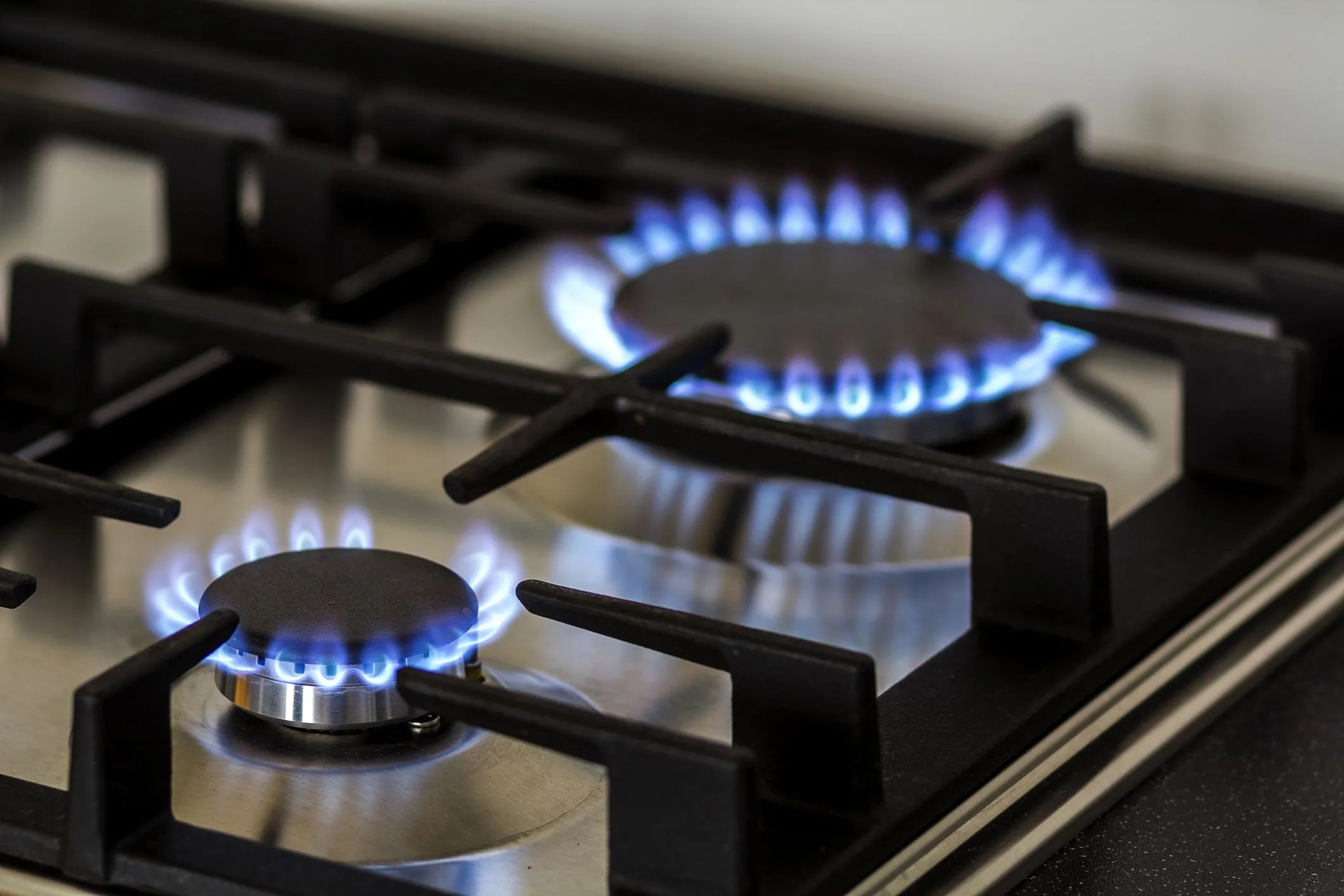 natural gas burning on kitchen gas stove in the dark panel from steel with a gas ring burner on a black background, close up shooting