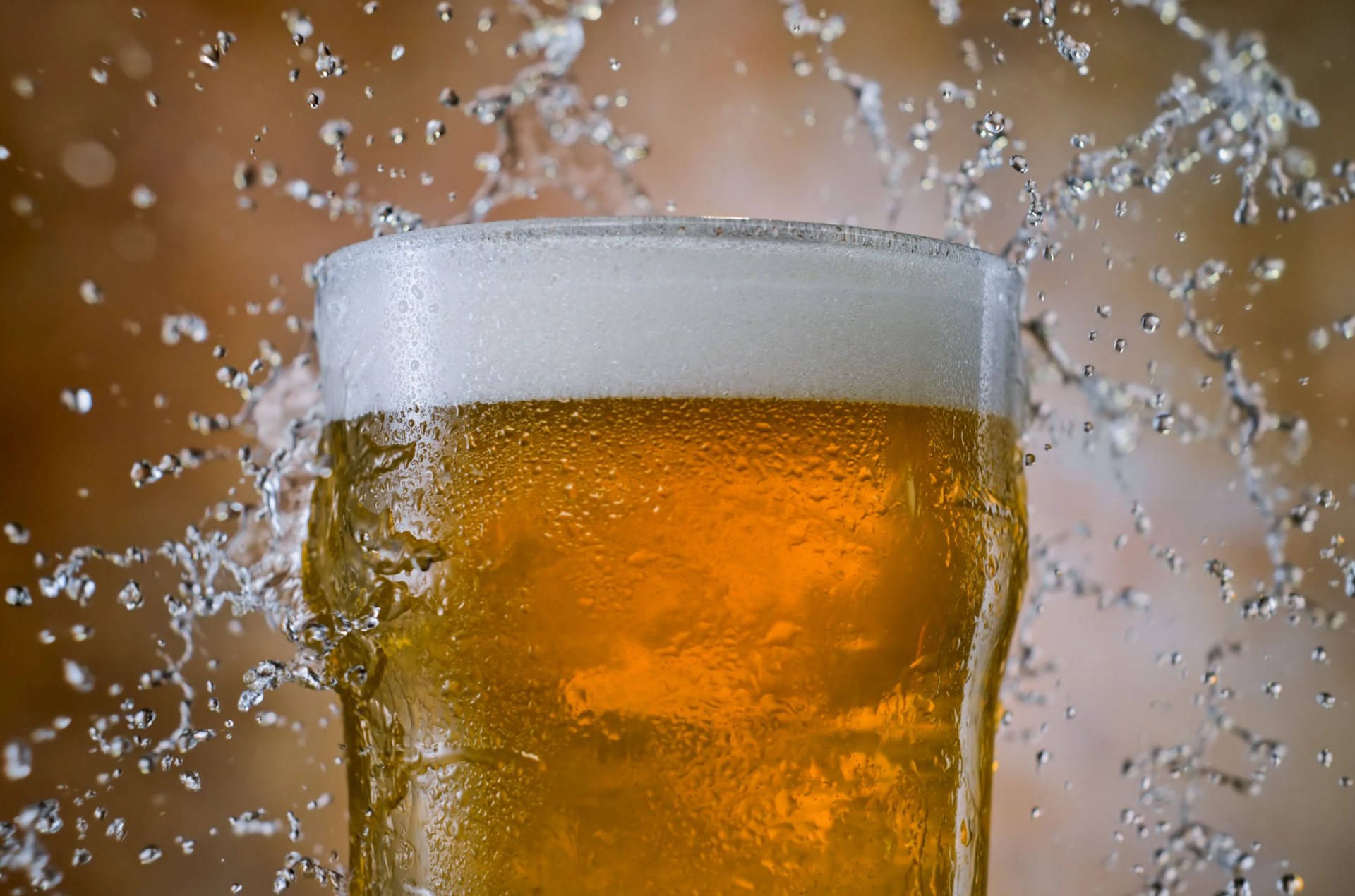 close up of glass of beer with water splashing from behind