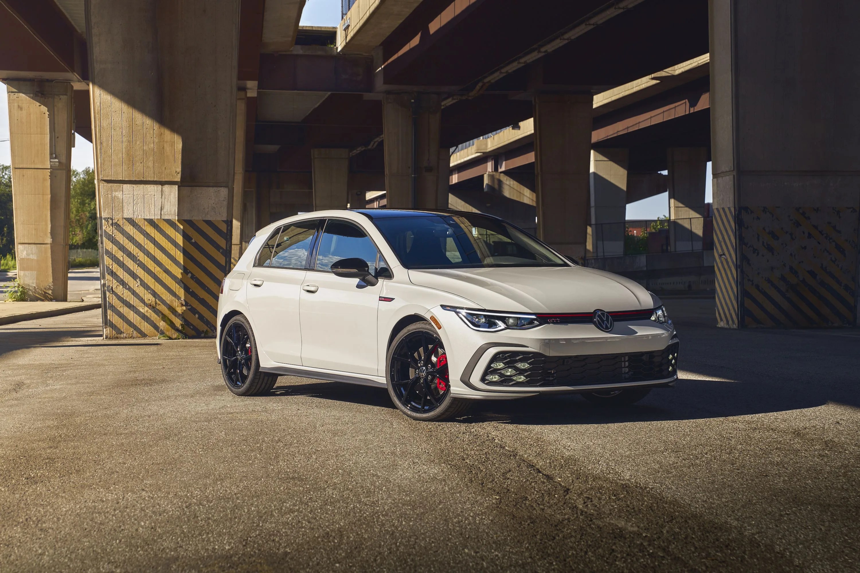 white volkswagen golf gti parked under a highway