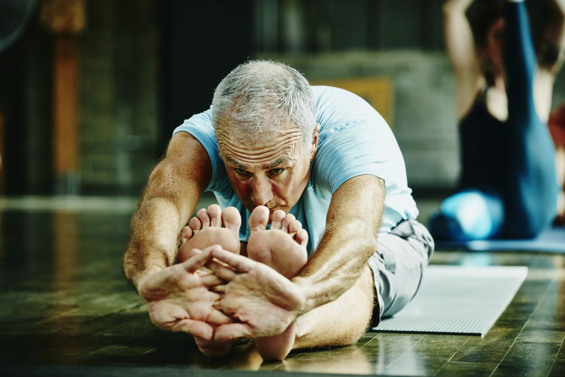 man in seated forward bend pose during yoga class