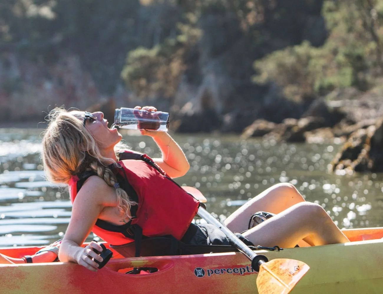 woman drinking from water bottle in kayak