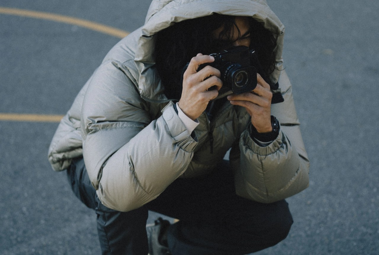 angel rodriguez crouched down taking a picture while wearing a goldwin parka