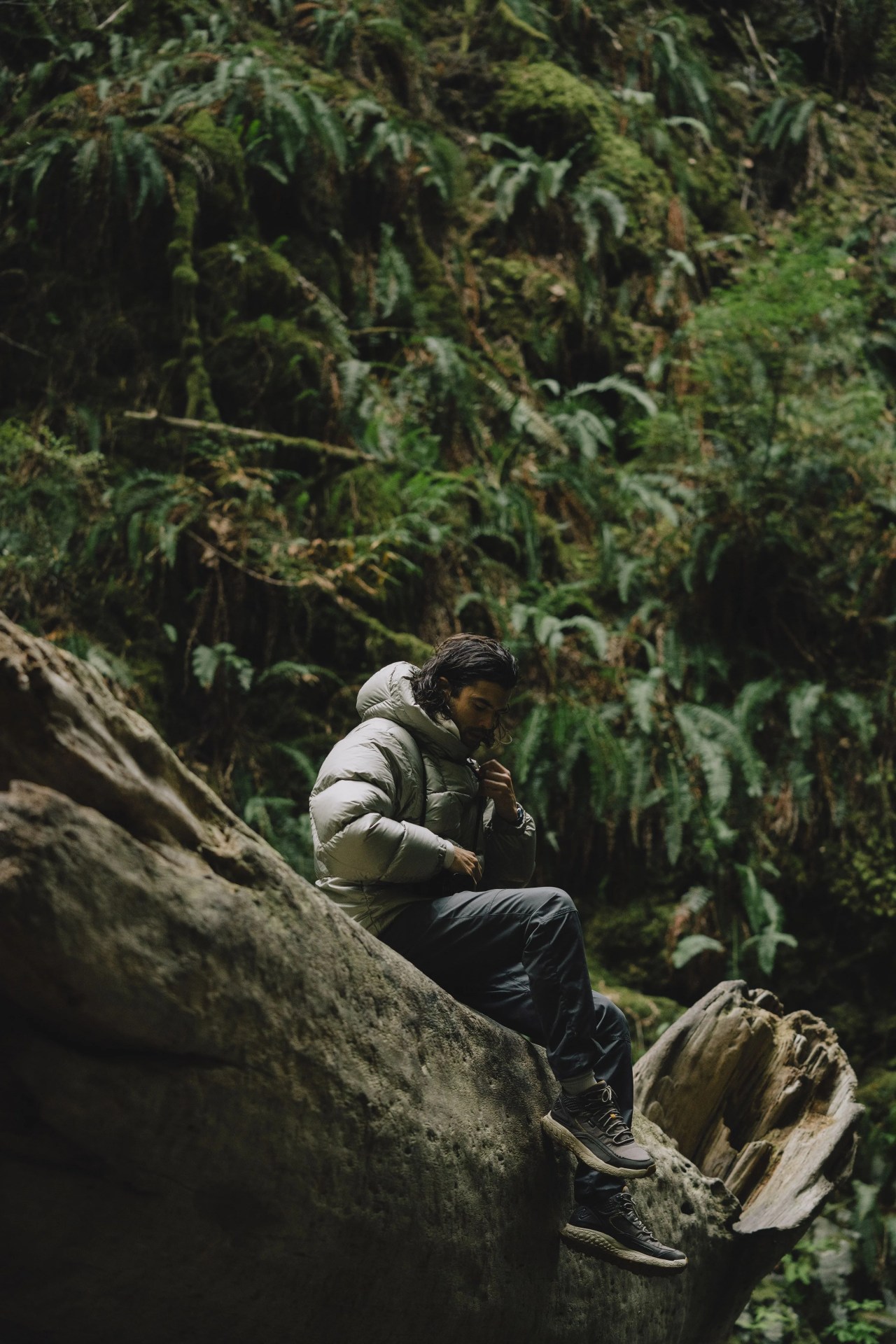 angel rodriguez sitting on a rock in a forest wearing a goldwin parka