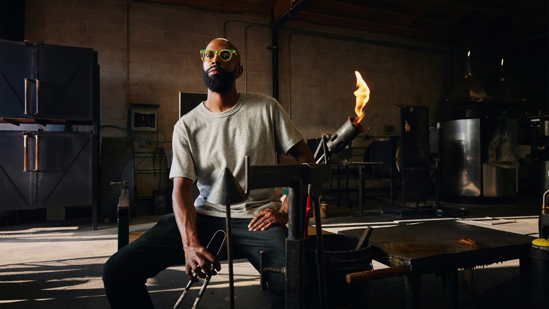 Cedric Mitchell sitting down carrying glass blowing torch