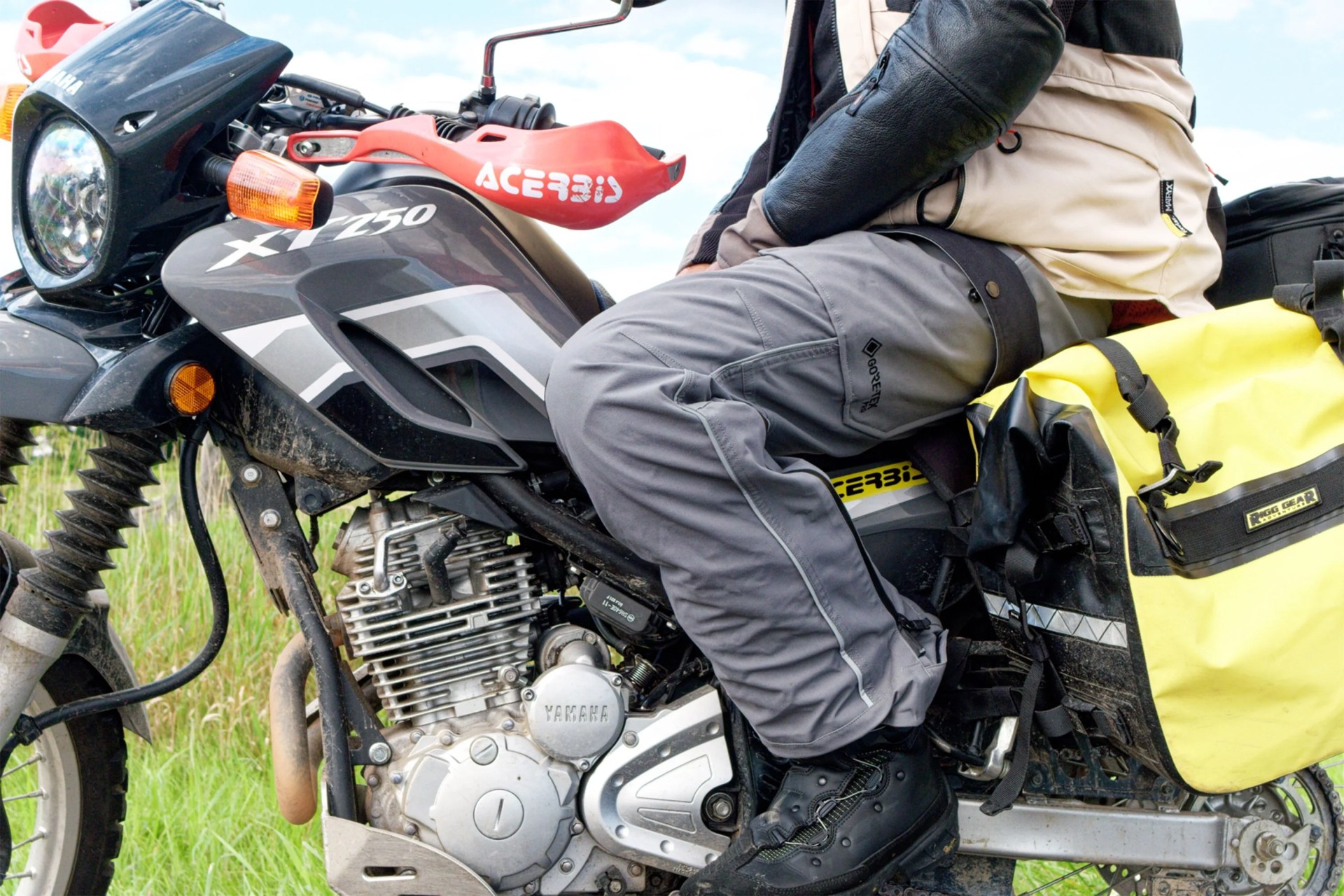 a man sitting on a motorcycle wearing motorcycle rain pants