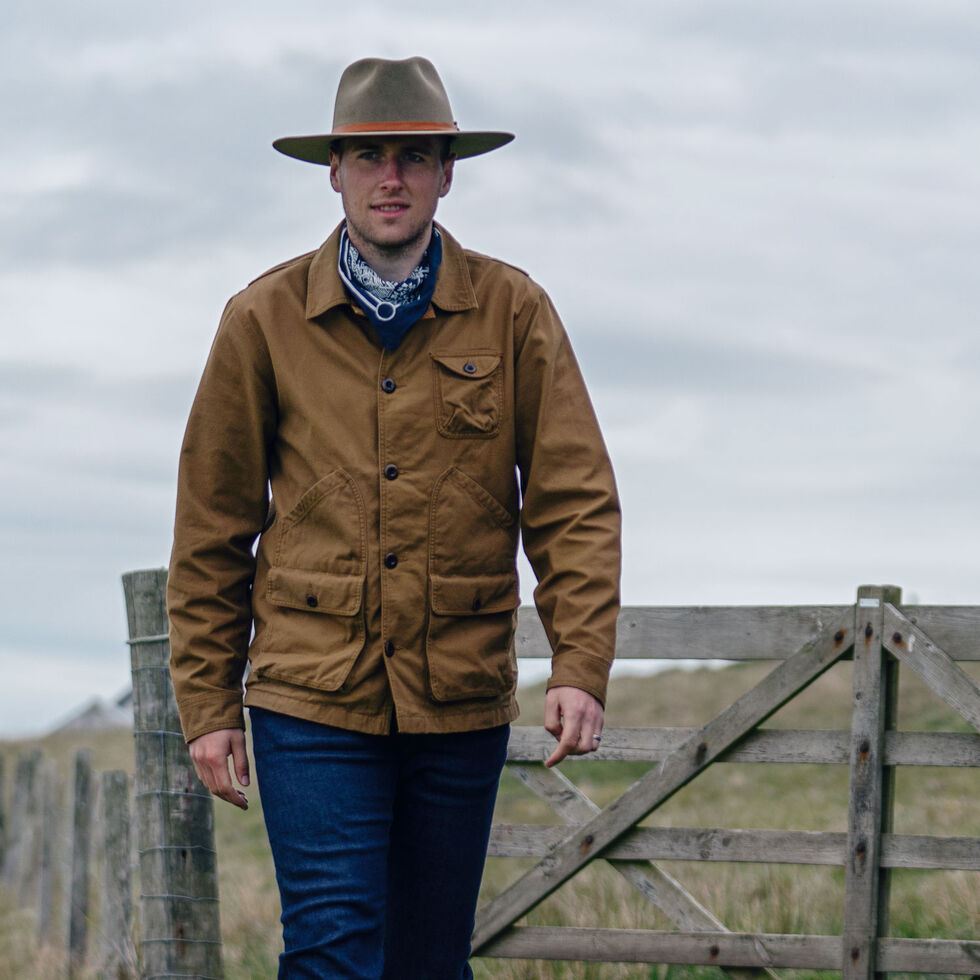 person wearing waxed canvas jacket in field