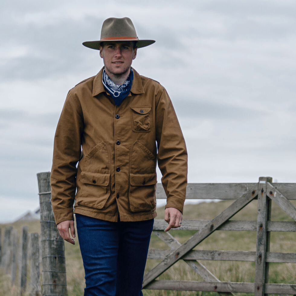 person wearing waxed canvas jacket in field