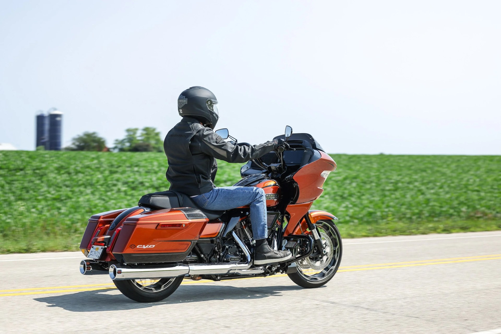 harley davidson motorcycle being ridden past green field