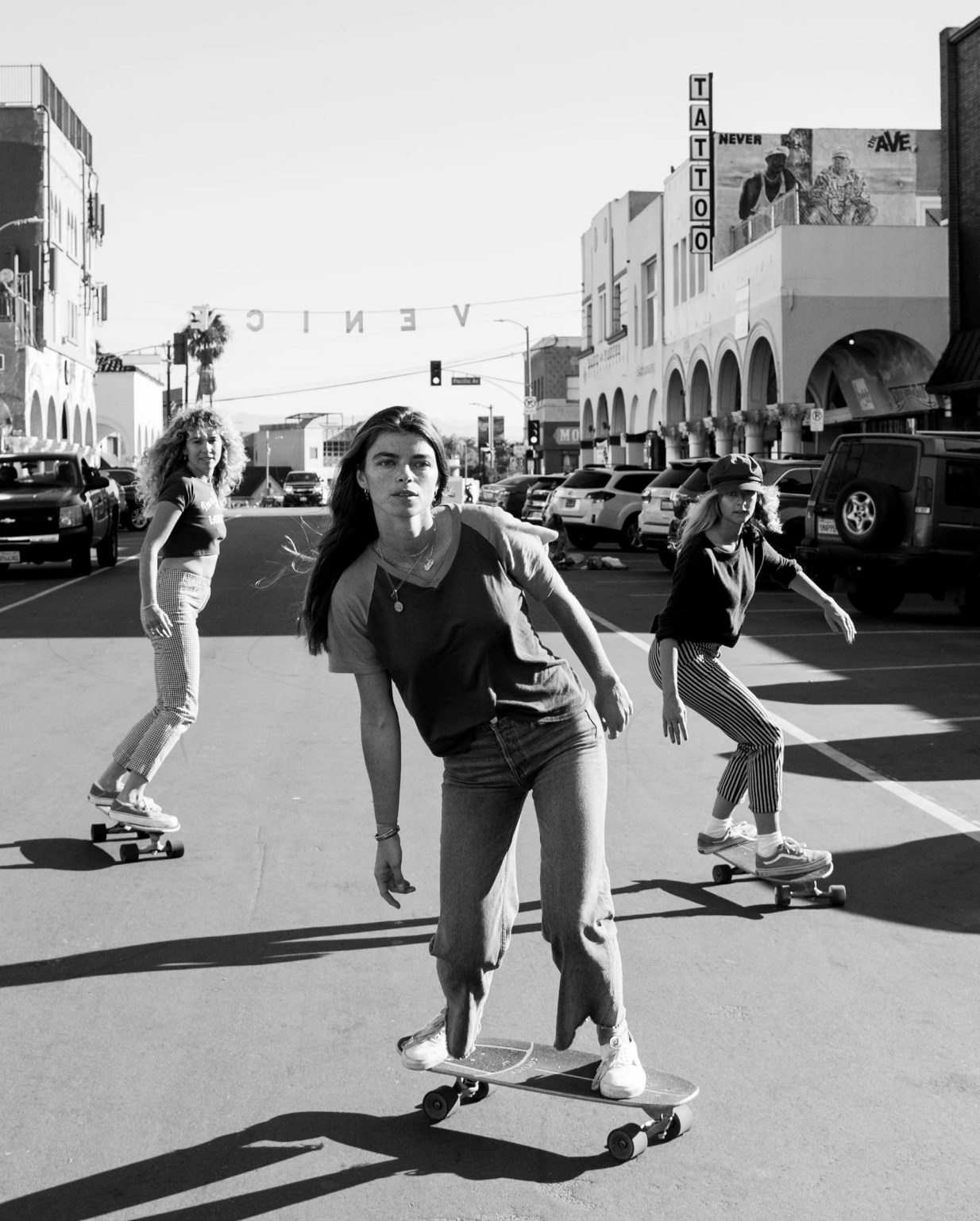 a black and white photo of three girls skateboarding in venice