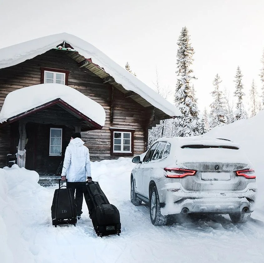 a person rolling a ski bag to a cabin