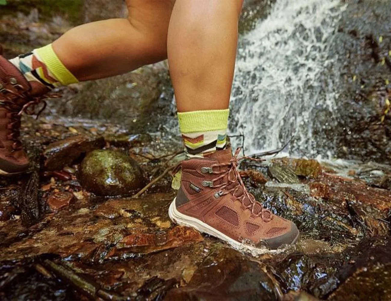a person wearing hiking boots through rocks and water