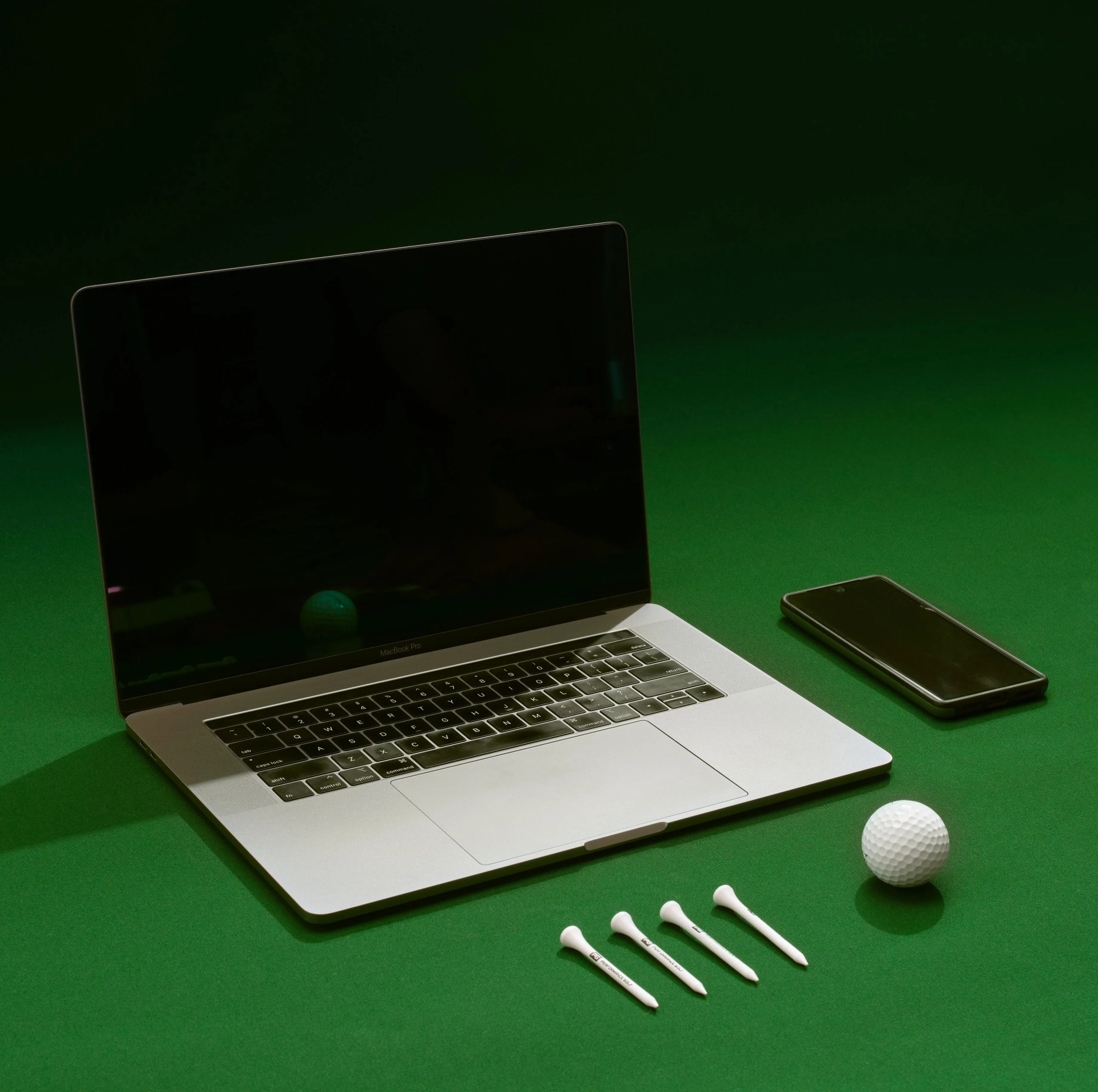 performance golf ball, tee, laptop and cell phone