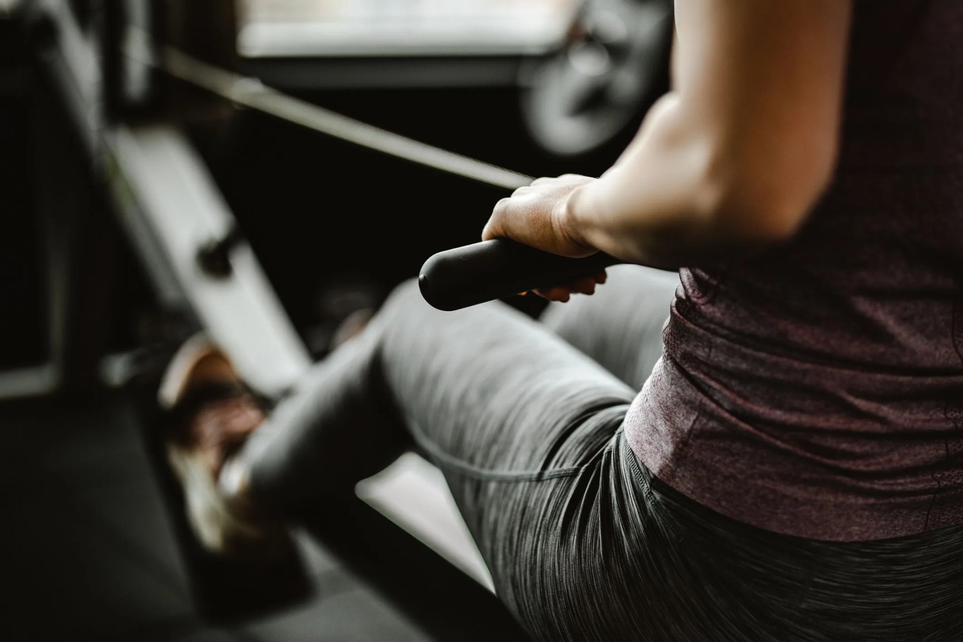 close up of unrecognizable female athlete having sports training on rowing machine in a gym