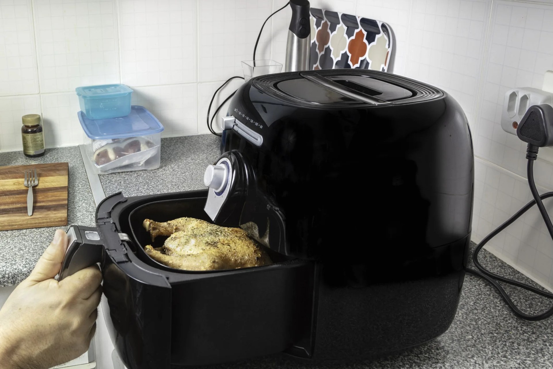 checking the roasted chicken in the hot air fryer oven in the kitchen