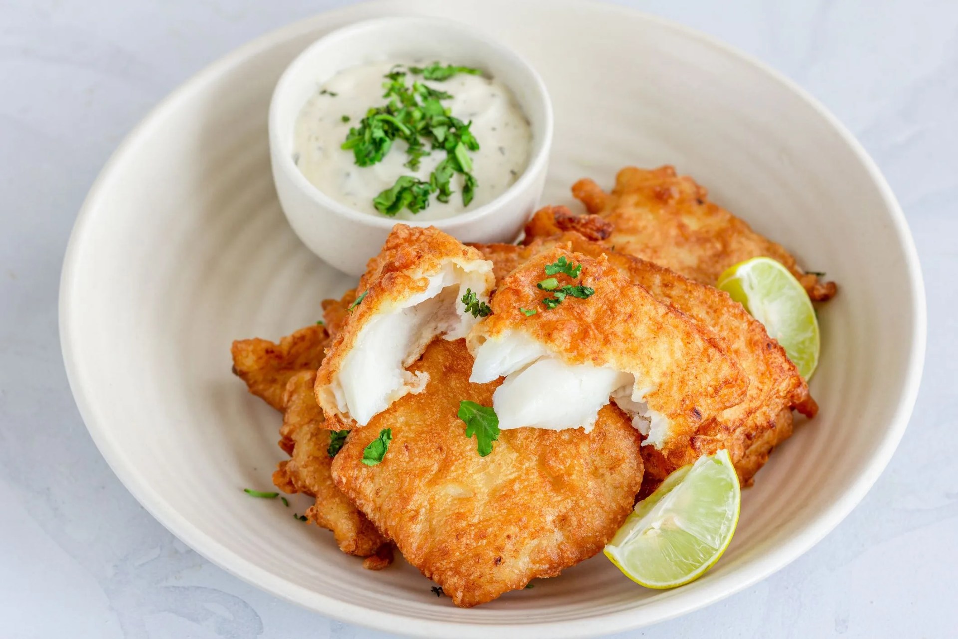 delicious fried fish with in a plate with lemon and white dip sauce, fish appetizer horizontal close up photo on white background