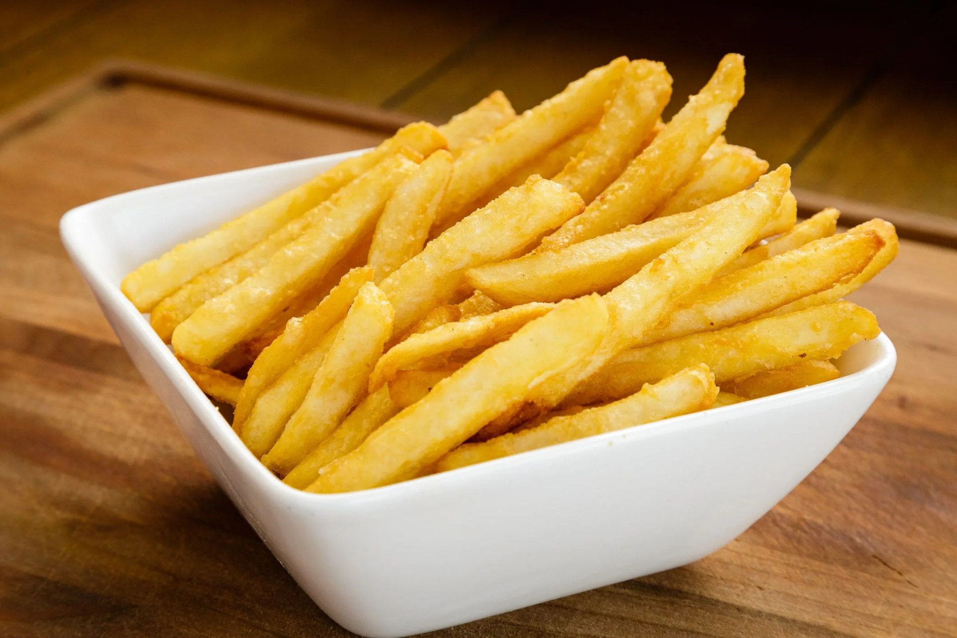 french fries on a white rectangular bowl placed on a wooden board