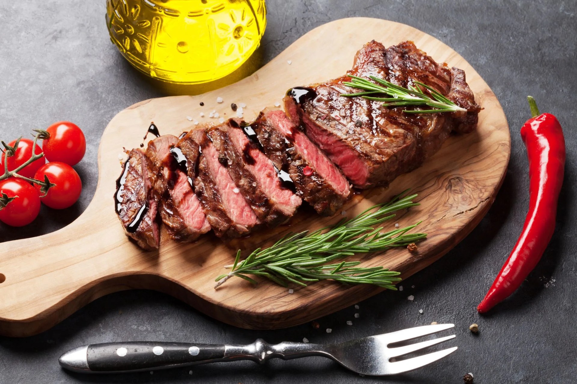 grilled striploin sliced steak on cutting board over stone table
