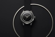 black and white image of a watch on a table and a large steel ring