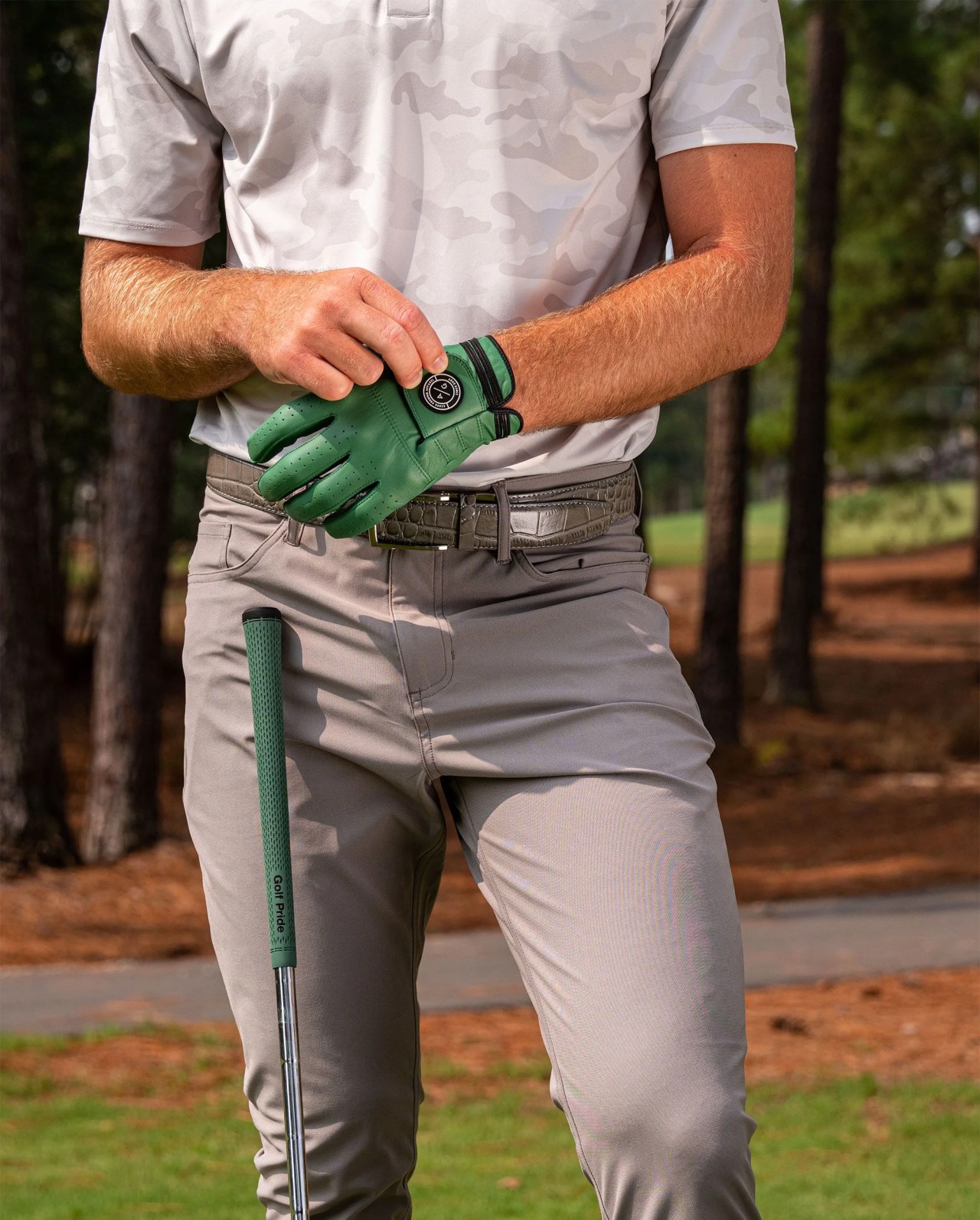 man wearing asher golf glove with golf cub leaning on right thigh