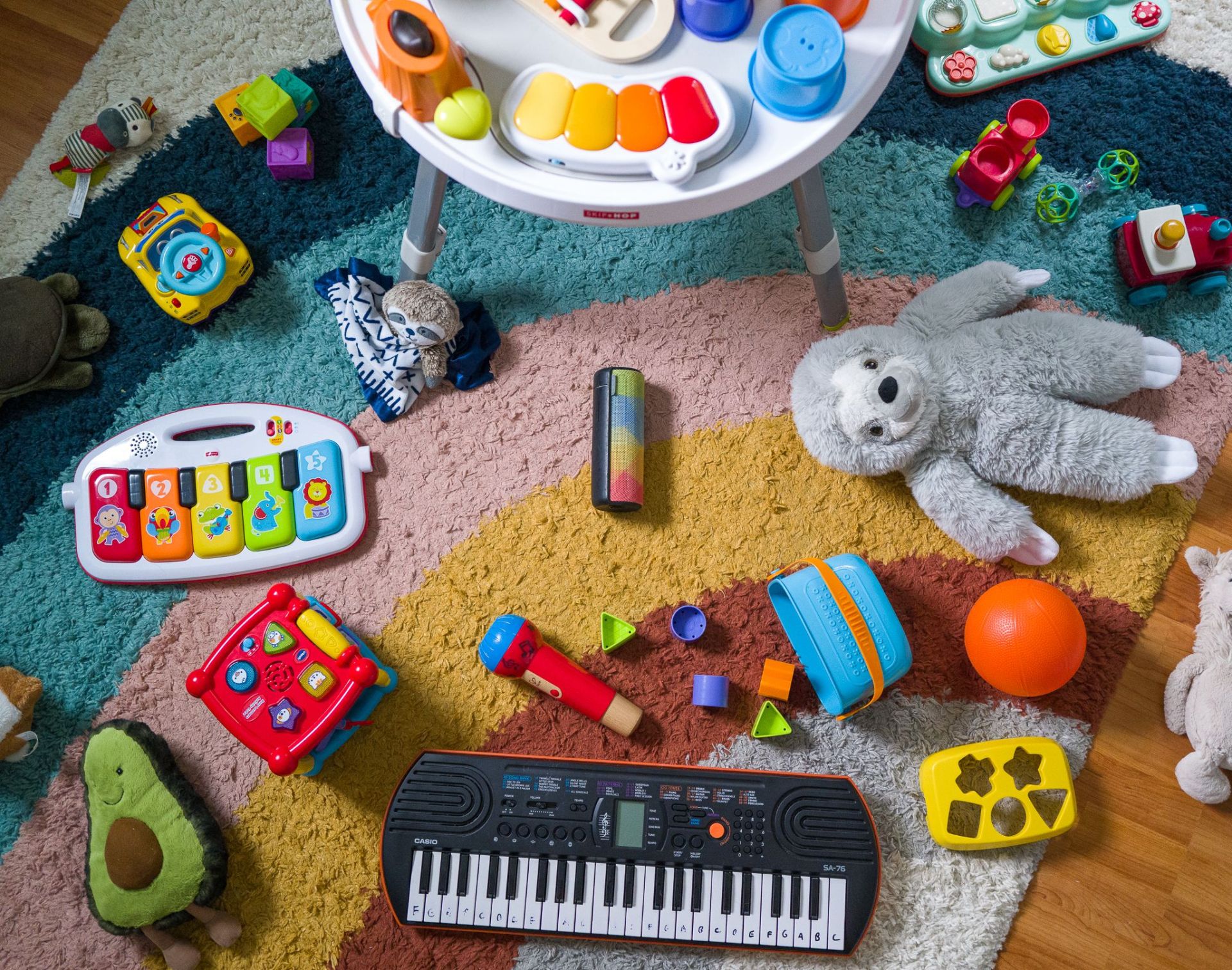 a ue boom speaker on a carpet surrounded by baby toys