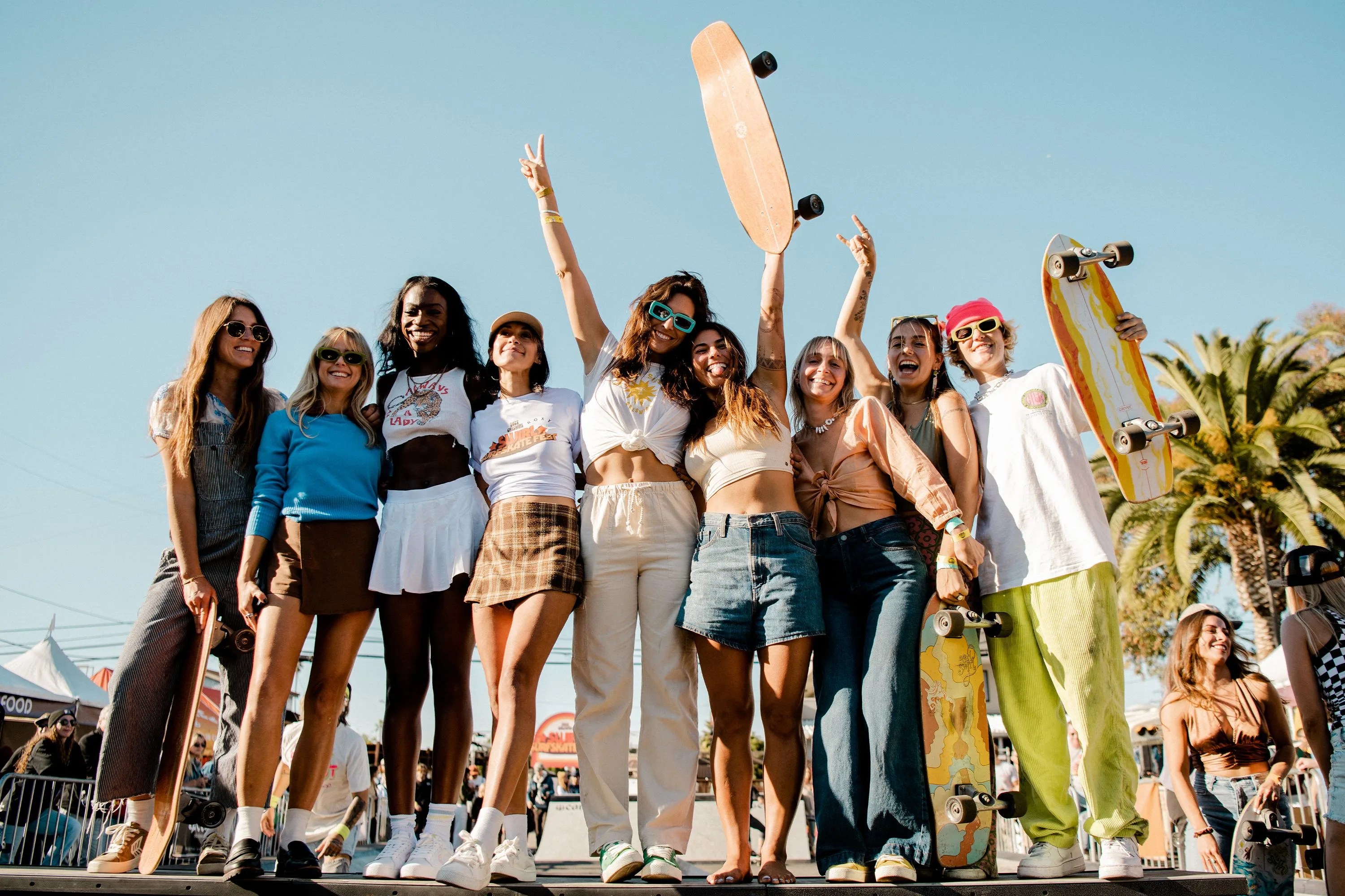 a group of girls posing for a picture holding skateboards