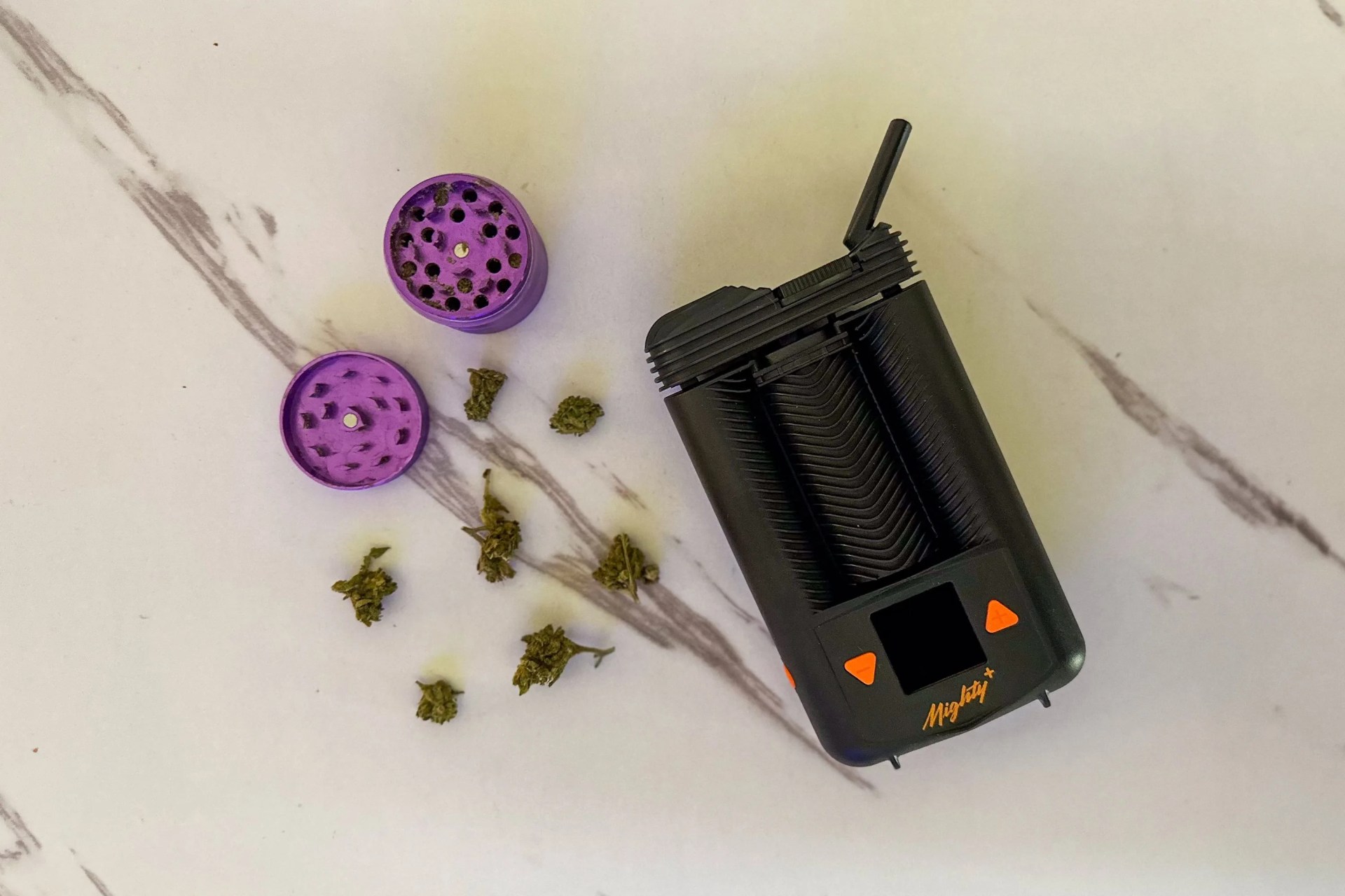 mighty plus weed vape on a table with weed flower and a grinder