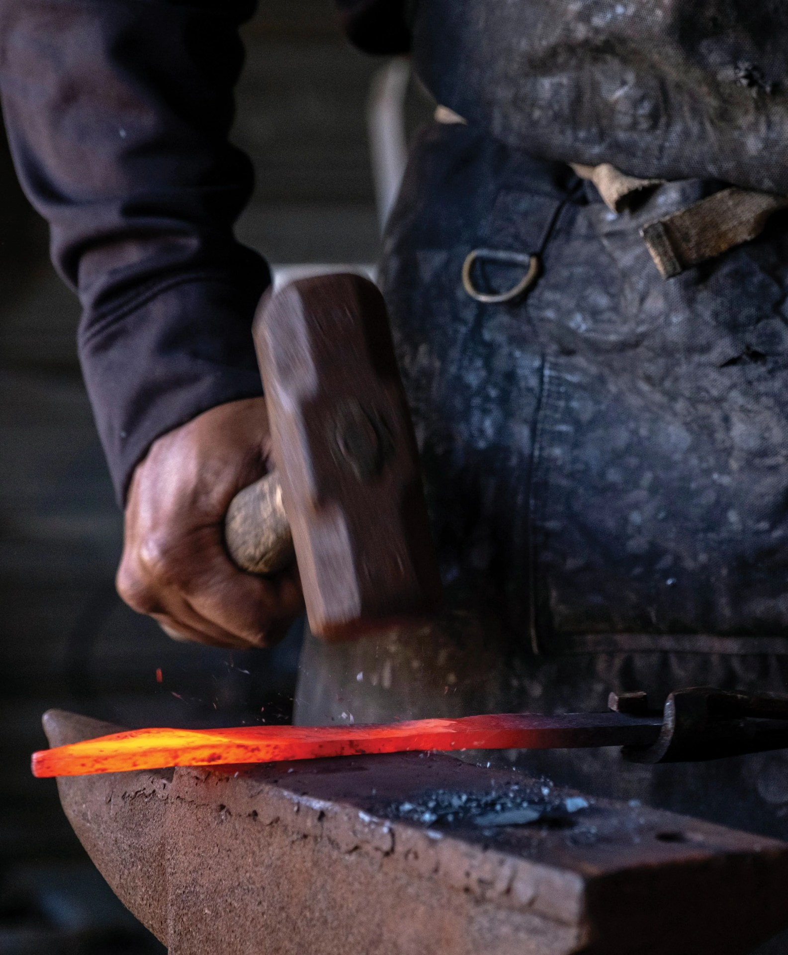 quintin middleton uses a hammer to shape a piece of carbon steel into a knife after its removed from the forge