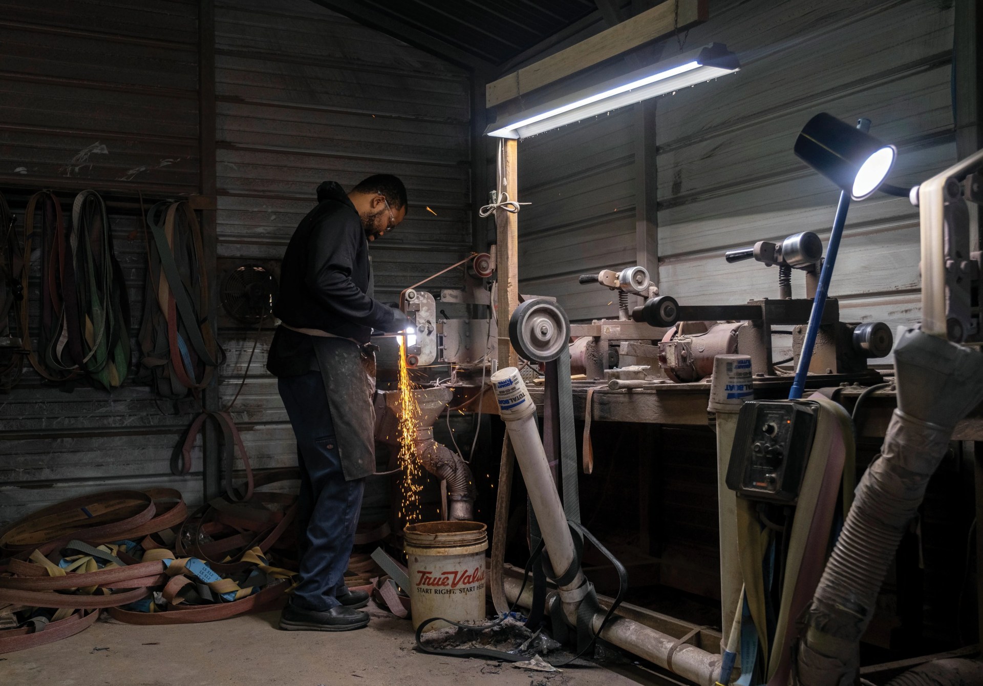 quintin middleton uses a grinder to sharpen a stainless steel chef knife