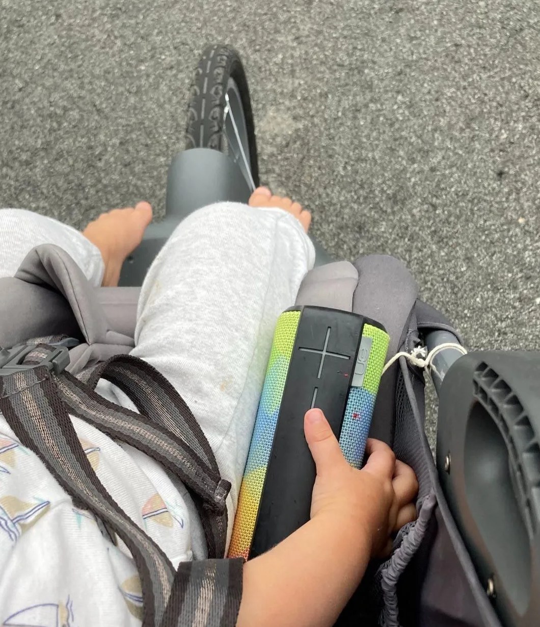 a baby's hand on a bluetooth speaker in a stroller