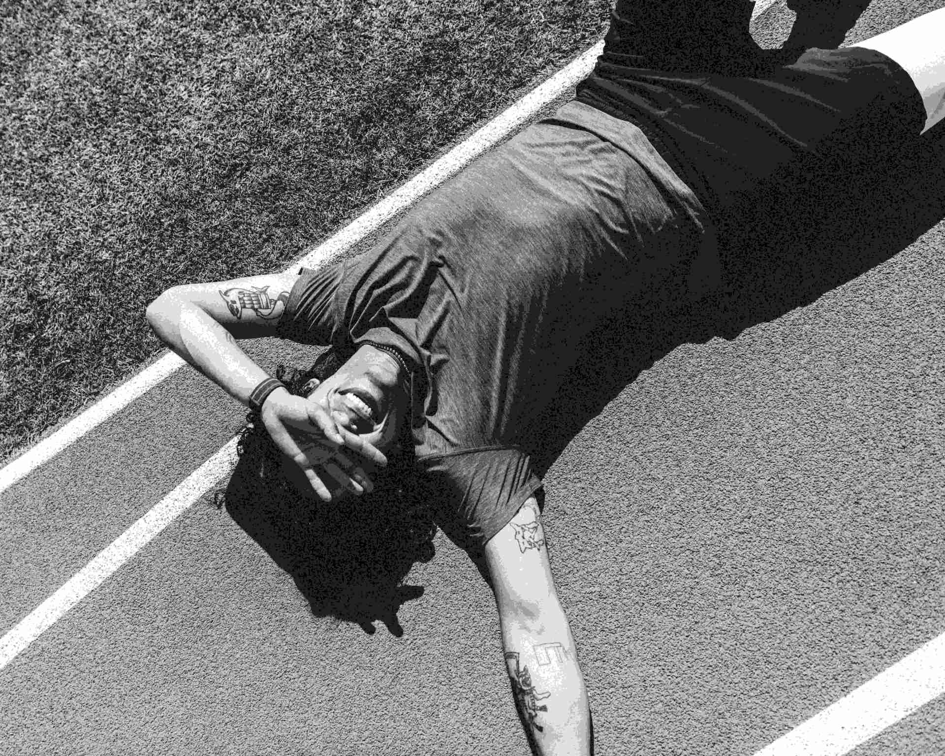 man laying on the ground on an outdoor track